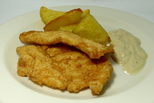 Battered turkey breasts with cheese sauce and baked potatoes