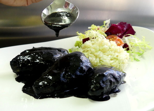 Squid stewed in their own ink with rice pilaf and salad 