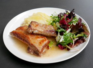 Roasted pork ribs with baked potatoes and salad
