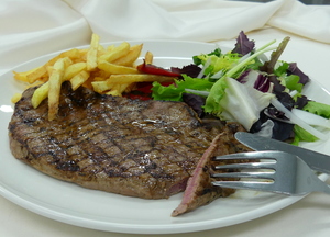 Filete a la plancha con ensalada, piquillos y patatas fritas