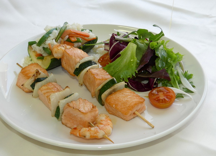 Brocheta de salmón con ensalada y calabacín relleno de arroz y verduras.